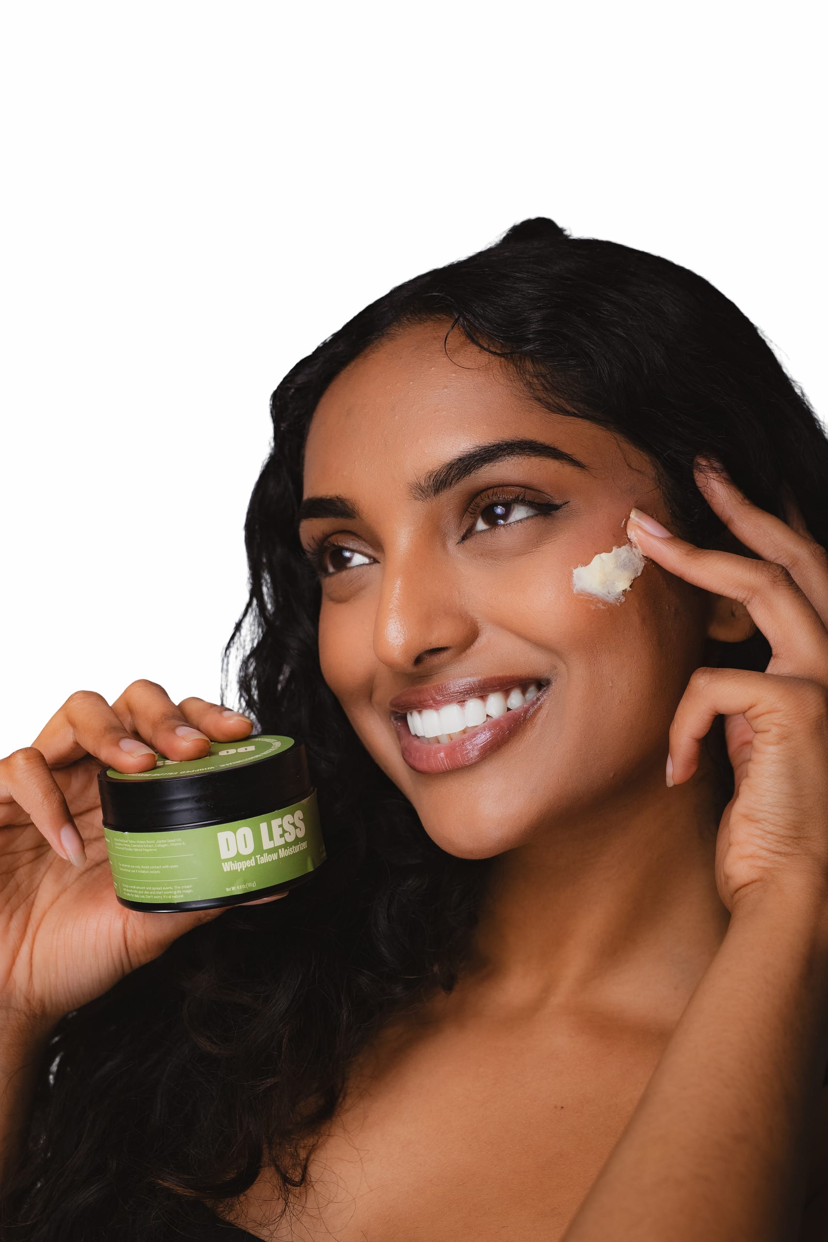 Beauty test shot holding a Do Less moisturizer jar, product on the cheek