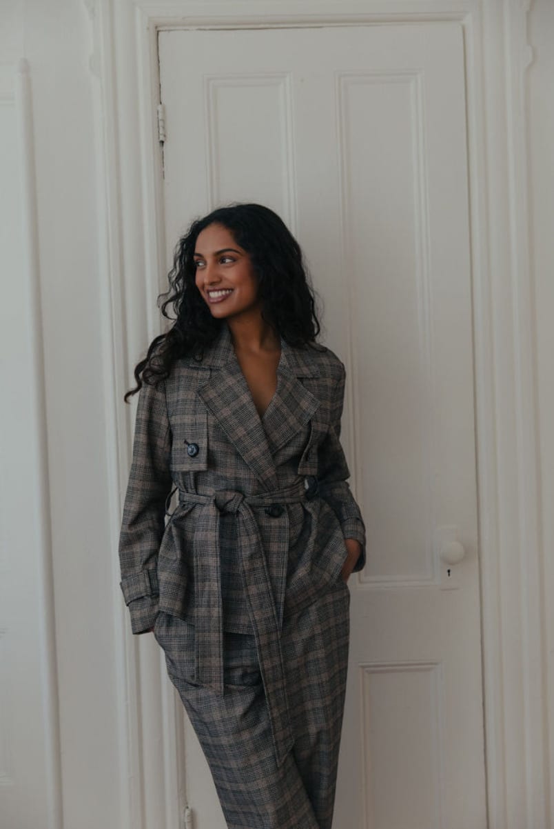 Standing in a grey plaid suit beside a panelled white door