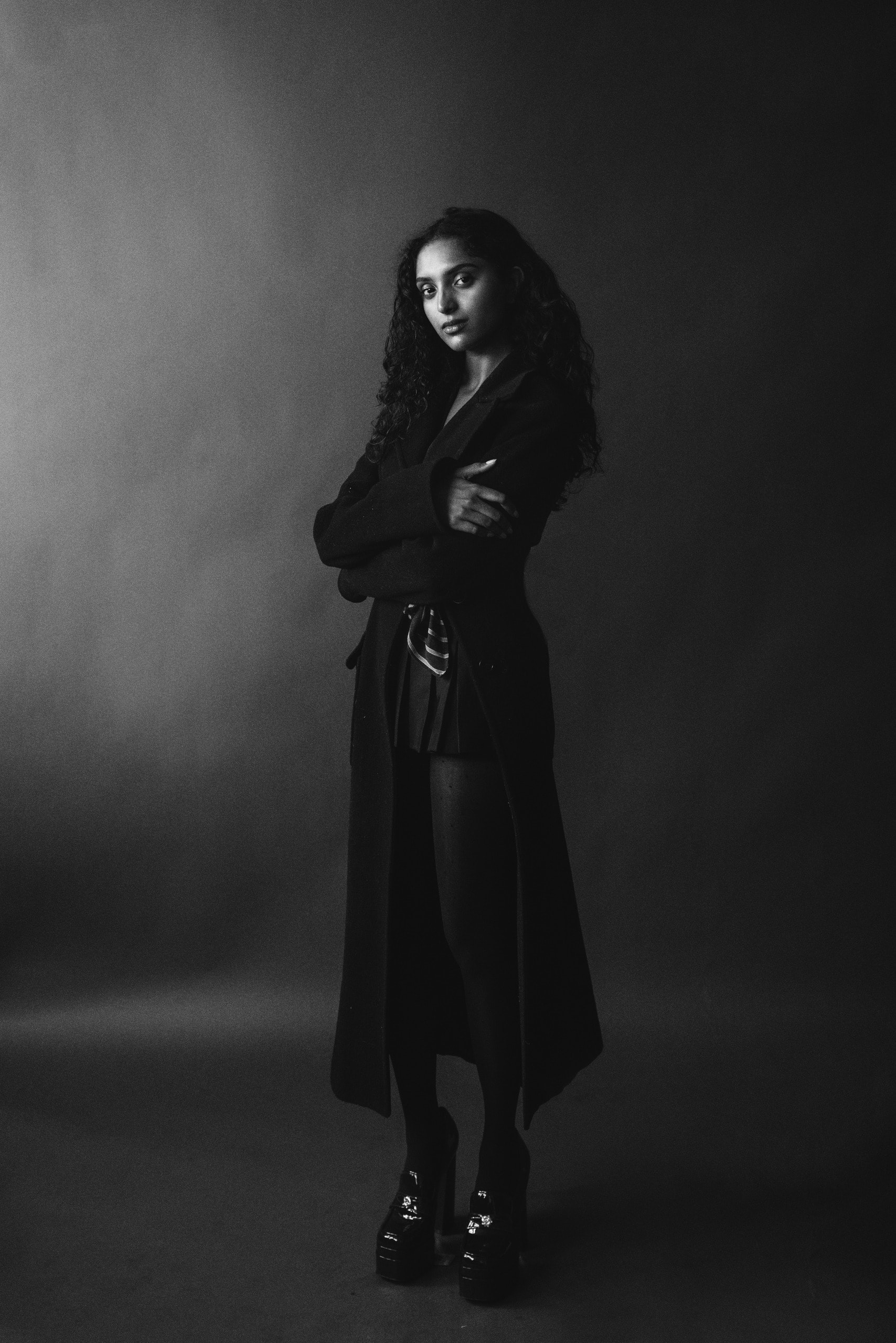Black and white editorial, full length in a long black coat and platform boots